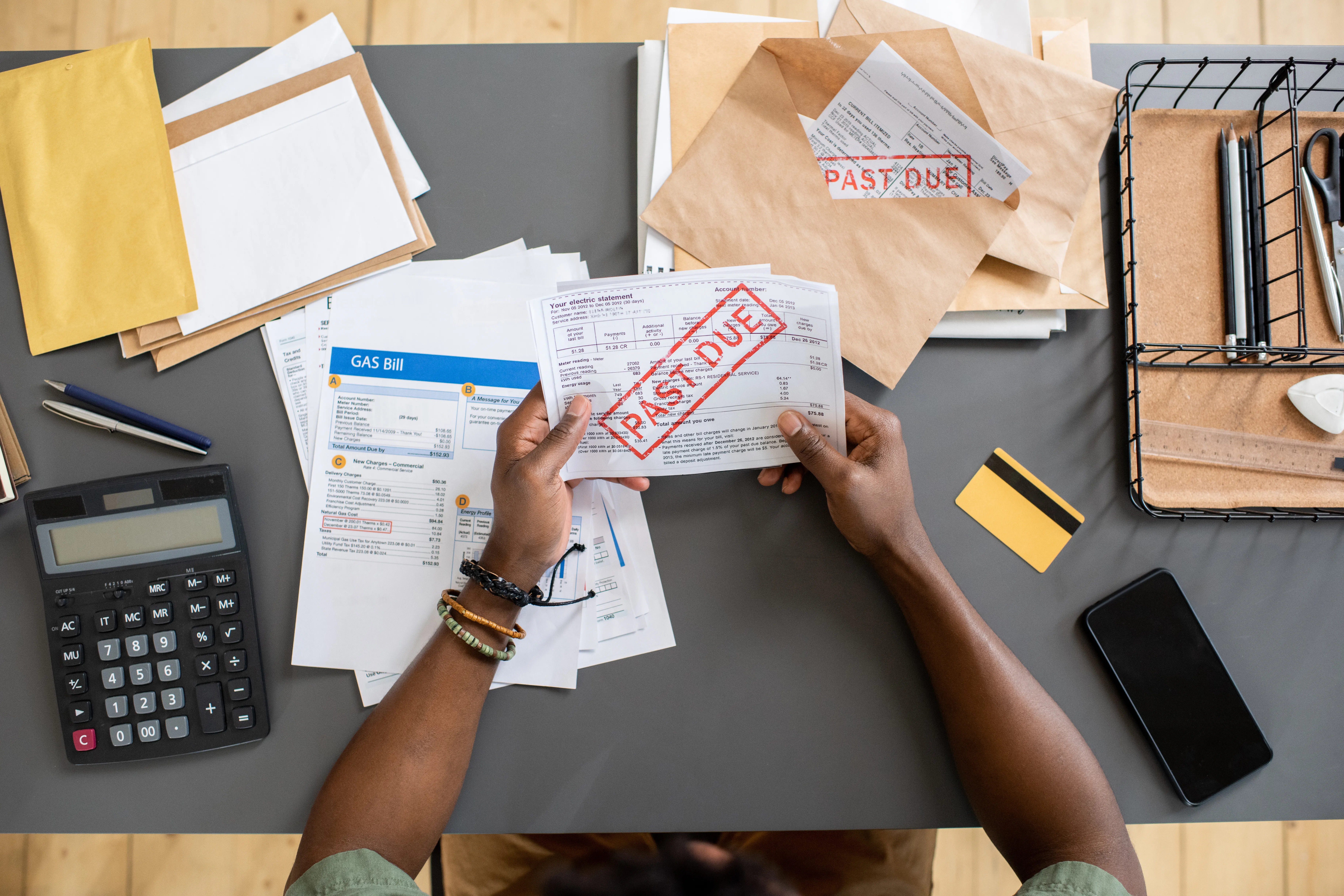 top view of a young man looking at a stack of unpaid bills